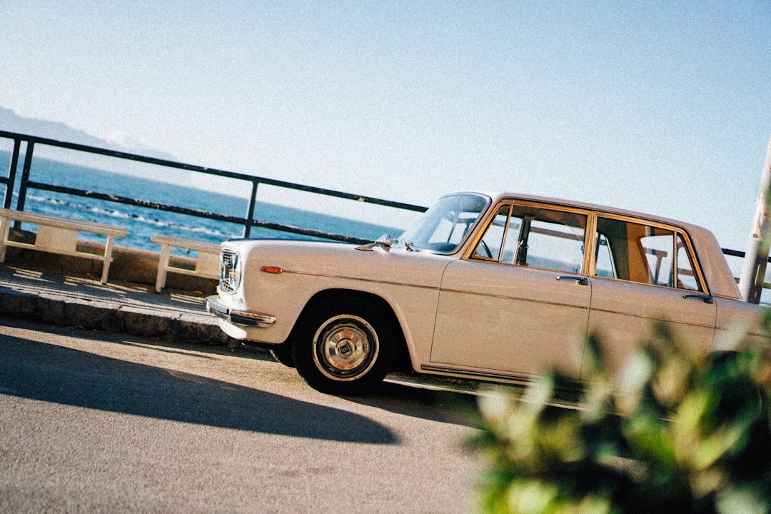 Vintage sports car driving along a coastal road at sunset near Punta del Este